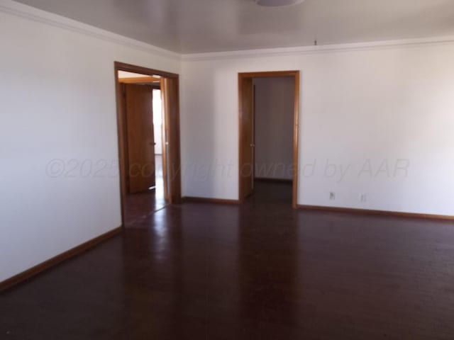 unfurnished room featuring baseboards, wood finished floors, and crown molding
