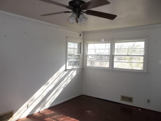 spare room with a ceiling fan, visible vents, baseboards, and wood finished floors