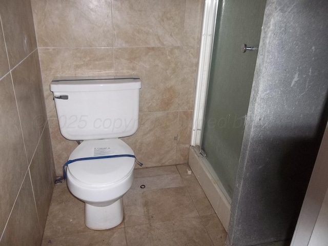 bathroom featuring tile walls, a shower with shower door, toilet, and tile patterned floors