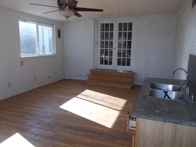 interior space featuring a sink, wood finished floors, brick wall, baseboards, and ceiling fan