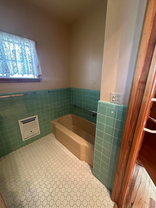 bathroom featuring tile walls, a garden tub, and a wainscoted wall