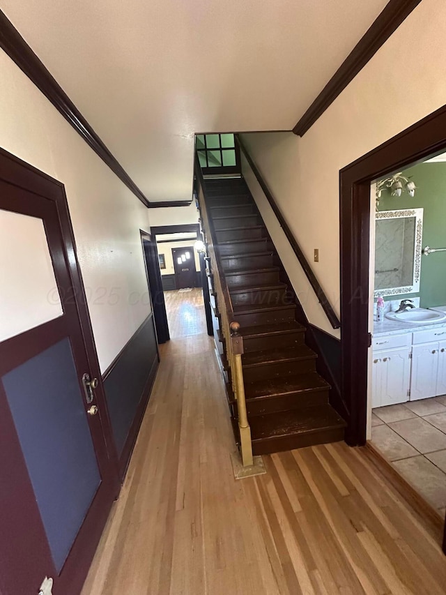 stairs featuring wood finished floors and ornamental molding