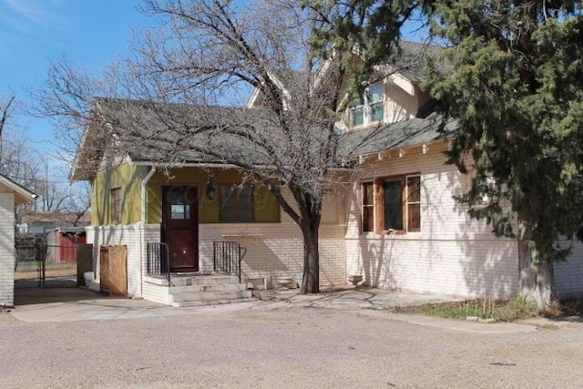 view of front of home with brick siding and fence