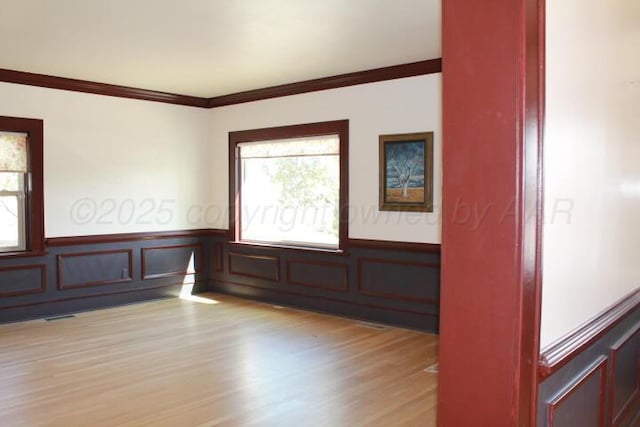 spare room with plenty of natural light, wood finished floors, and wainscoting