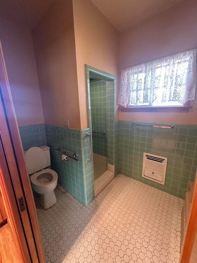 full bathroom with heating unit, a shower stall, wainscoting, tile walls, and toilet