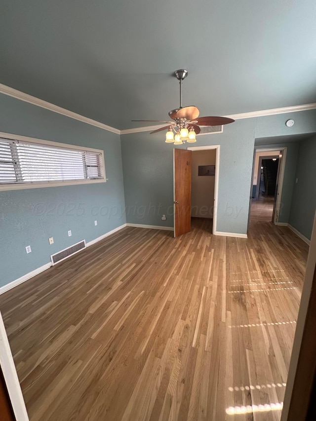 unfurnished room featuring visible vents, crown molding, baseboards, ceiling fan, and wood finished floors