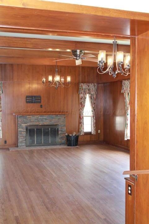 unfurnished living room with beamed ceiling, wood finished floors, and wood walls