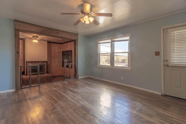 unfurnished living room featuring hardwood / wood-style flooring, ceiling fan, and a brick fireplace