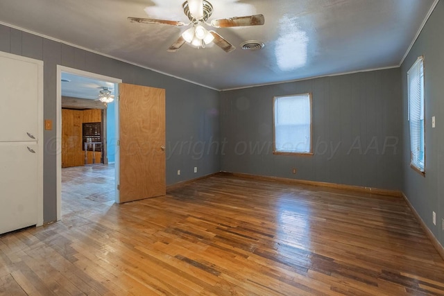 empty room with hardwood / wood-style floors, ceiling fan, a healthy amount of sunlight, and crown molding