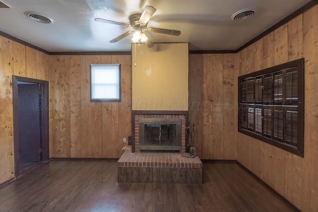 unfurnished living room with crown molding, a fireplace, dark wood-type flooring, and wooden walls