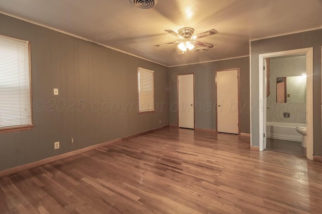 unfurnished bedroom featuring hardwood / wood-style flooring, ceiling fan, ornamental molding, and ensuite bathroom