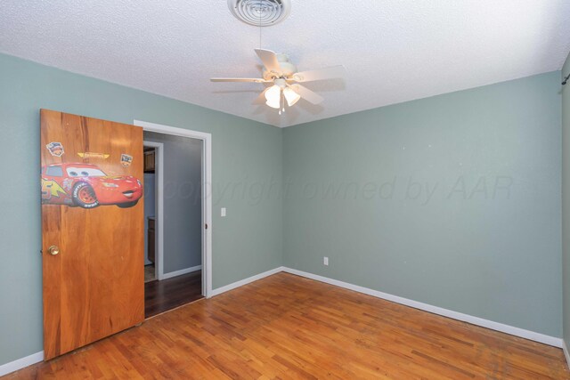 1209 S Main St, Shamrock, TX 79079 - unfurnished bedroom featuring wood finished floors, a textured ceiling, and a ceiling fan