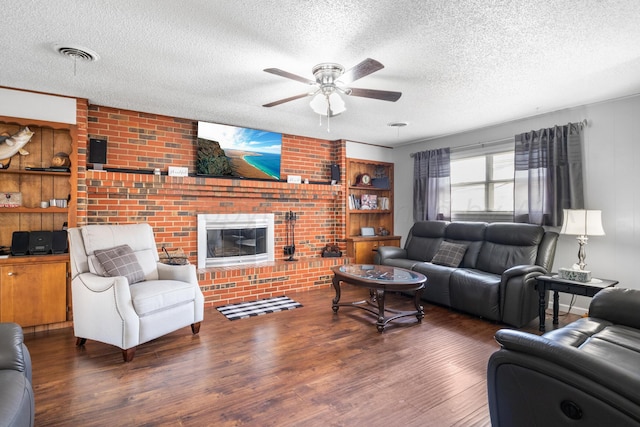 living room featuring a fireplace, dark wood-type flooring, a textured ceiling, and ceiling fan