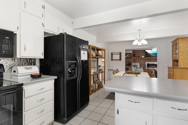 kitchen with hanging light fixtures, white cabinetry, and black appliances