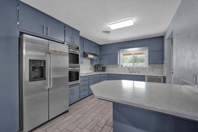 3412 Sunlite St, Amarillo, TX 79109 - kitchen with stainless steel appliances, blue cabinets, under cabinet range hood, decorative backsplash, and a textured wall
