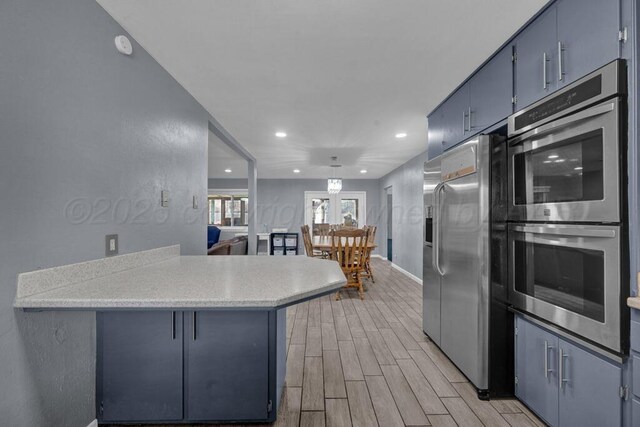 3412 Sunlite St, Amarillo, TX 79109 - kitchen with stainless steel appliances, blue cabinetry, recessed lighting, light wood-style floors, and a peninsula