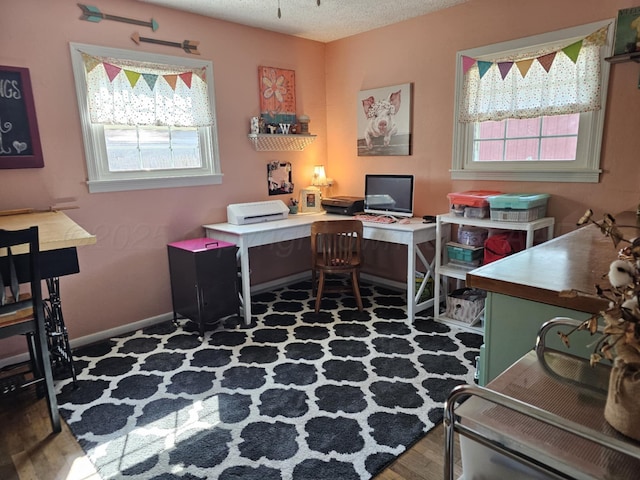 office space with plenty of natural light, wood finished floors, baseboards, and a textured ceiling