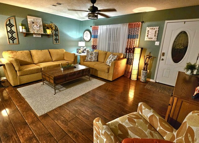 living area featuring visible vents, a textured ceiling, hardwood / wood-style floors, and a ceiling fan