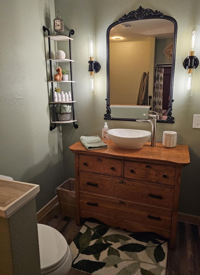 bathroom with vanity, toilet, wood finished floors, and baseboards