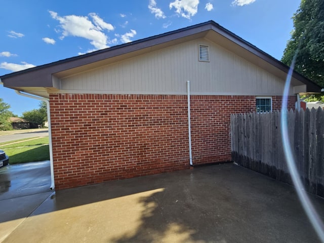 view of home's exterior with brick siding and fence