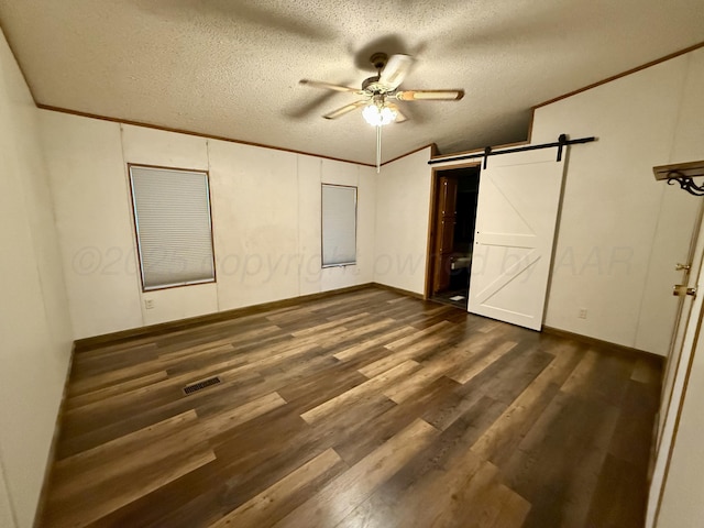 2700 Potter Dr, Amarillo, TX 79108 - unfurnished bedroom featuring a textured ceiling, visible vents, dark wood finished floors, a barn door, and ornamental molding