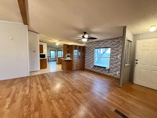 2700 Potter Dr, Amarillo, TX 79108 - unfurnished living room with a ceiling fan, a textured ceiling, wood finished floors, and brick wall