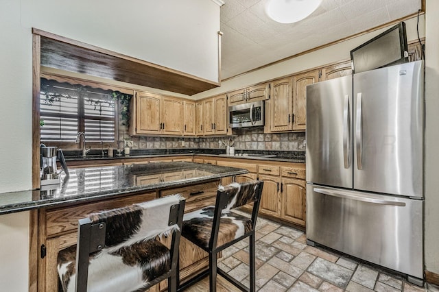 2229 Charles St, Pampa, TX 79065 - kitchen with stainless steel appliances, backsplash, dark stone counters, a breakfast bar, and light stone finish floors