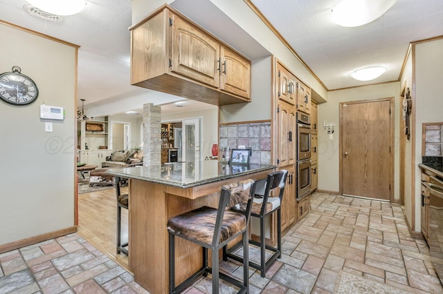 2229 Charles St, Pampa, TX 79065 - kitchen with a breakfast bar area, dark stone countertops, brick patterned floors, and double oven