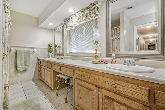 2229 Charles St, Pampa, TX 79065 - bathroom featuring double vanity, tile patterned floors, tile walls, and wainscoting