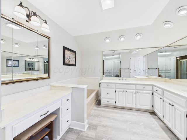 bathroom featuring a bath, lofted ceiling, and vanity