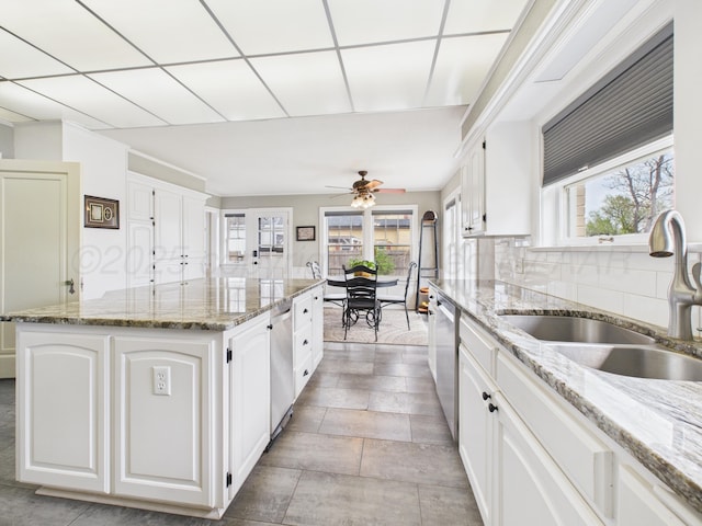 kitchen featuring white cabinetry, a center island, a wealth of natural light, and a sink