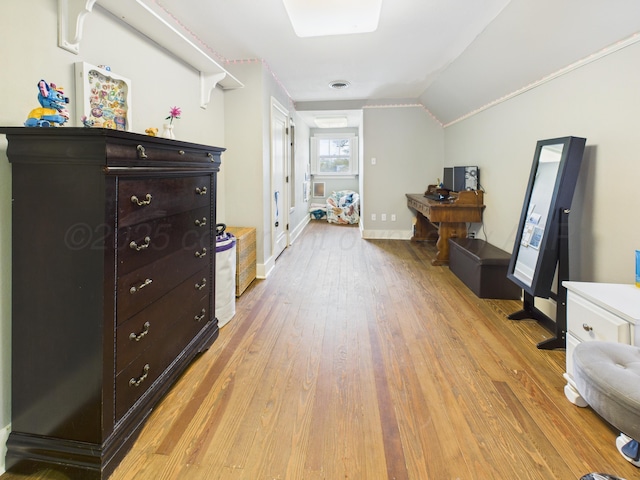 interior space with baseboards, vaulted ceiling, and light wood-type flooring