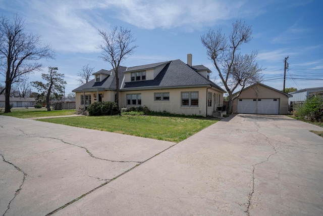 bungalow-style home with a garage, a chimney, a front yard, and an outbuilding