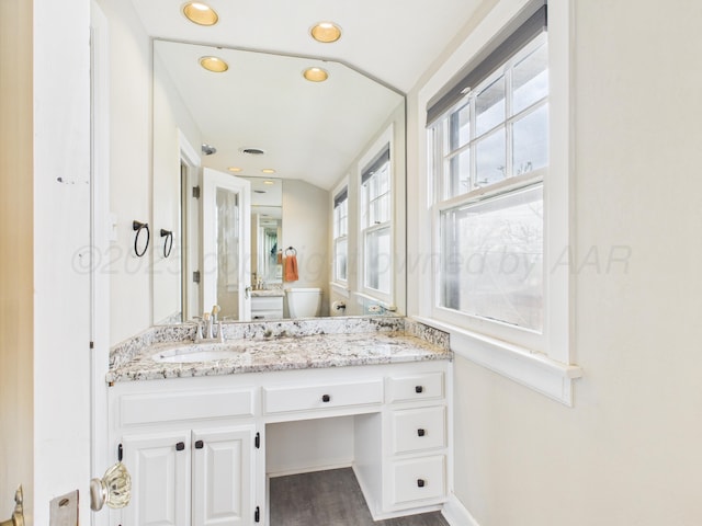 bathroom with recessed lighting, a sink, toilet, double vanity, and wood finished floors