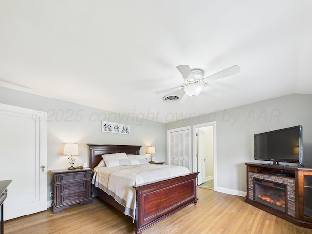bedroom with baseboards, visible vents, a ceiling fan, and light wood-style flooring