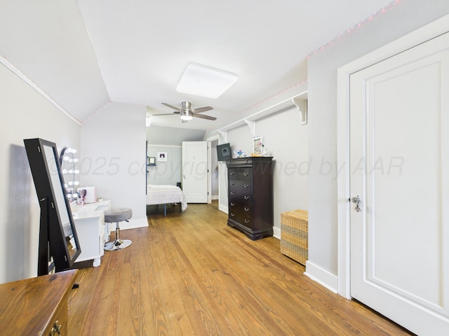 bedroom with baseboards, wood finished floors, ceiling fan, and lofted ceiling