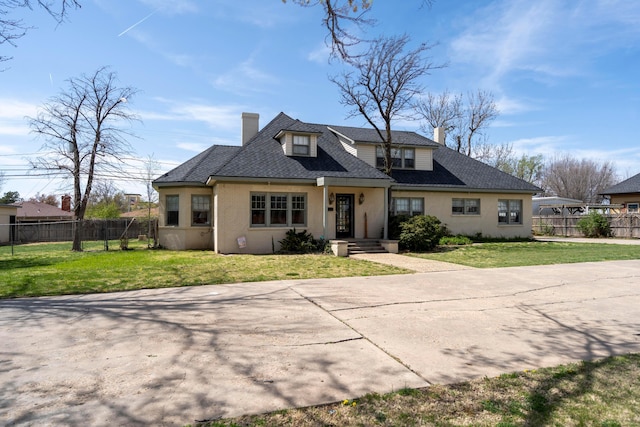 view of front of home featuring a chimney, fence, and a front lawn