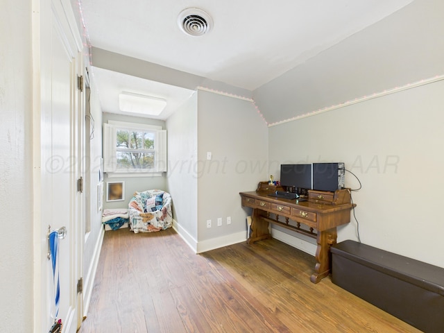 office featuring wood finished floors, visible vents, vaulted ceiling, and baseboards
