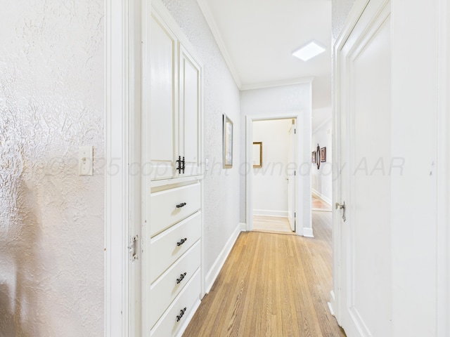 hall with baseboards, ornamental molding, and light wood-style floors
