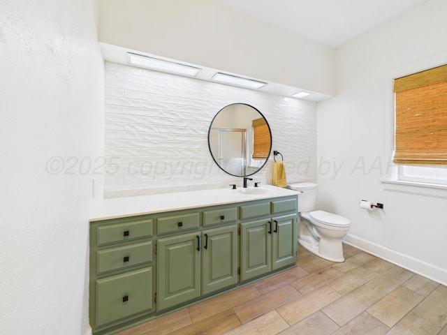 bathroom featuring toilet, wood finished floors, vanity, and baseboards