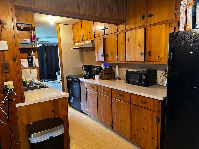 206 Dolomita St, Borger, TX 79007 - kitchen with black appliances, under cabinet range hood, brown cabinets, light countertops, and light flooring