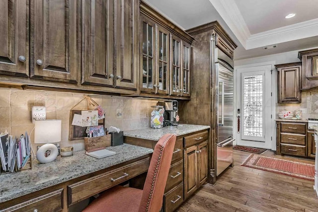 kitchen with glass insert cabinets, dark brown cabinets, ornamental molding, tasteful backsplash, and dark wood-style floors