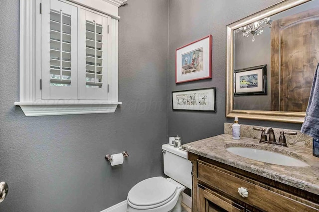 bathroom with toilet, baseboards, and vanity