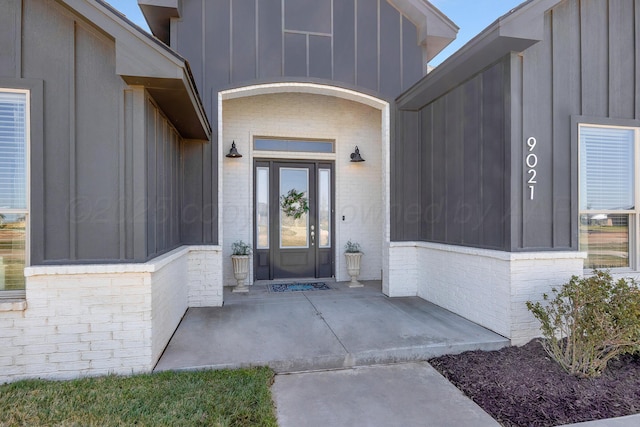 property entrance with board and batten siding and brick siding