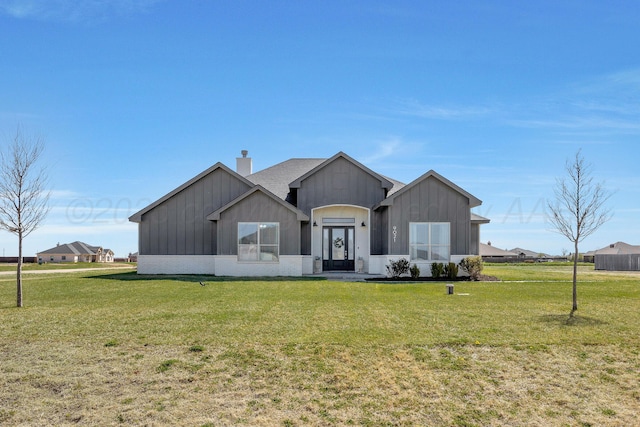 modern farmhouse with board and batten siding, a front yard, and a chimney