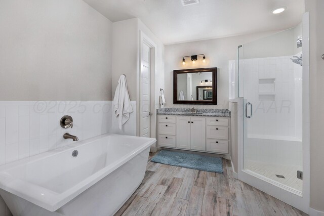 full bathroom featuring visible vents, a soaking tub, a shower stall, vanity, and wood finished floors
