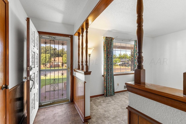 foyer with a textured ceiling, carpet floors, a wealth of natural light, and baseboards