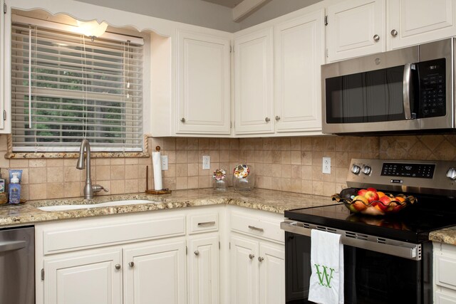 7133 Birkshire Dr, Amarillo, TX 79109 - kitchen with stainless steel appliances, a sink, tasteful backsplash, and white cabinets