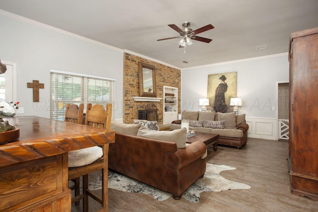7133 Birkshire Dr, Amarillo, TX 79109 - living area with ornamental molding, a ceiling fan, a brick fireplace, wood finished floors, and a decorative wall