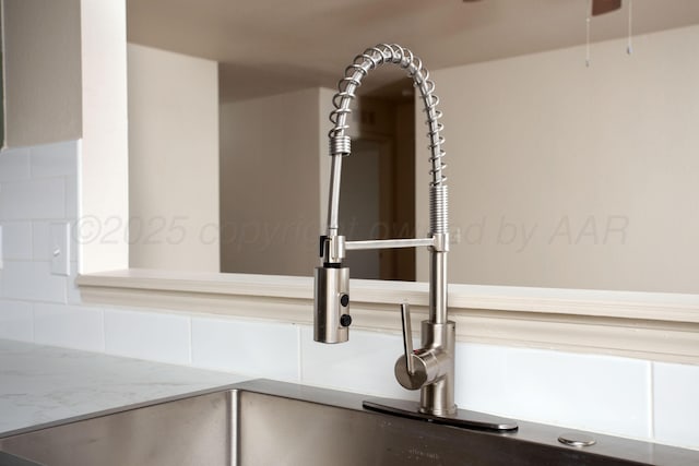 room details featuring light stone countertops, ceiling fan, decorative backsplash, and a sink